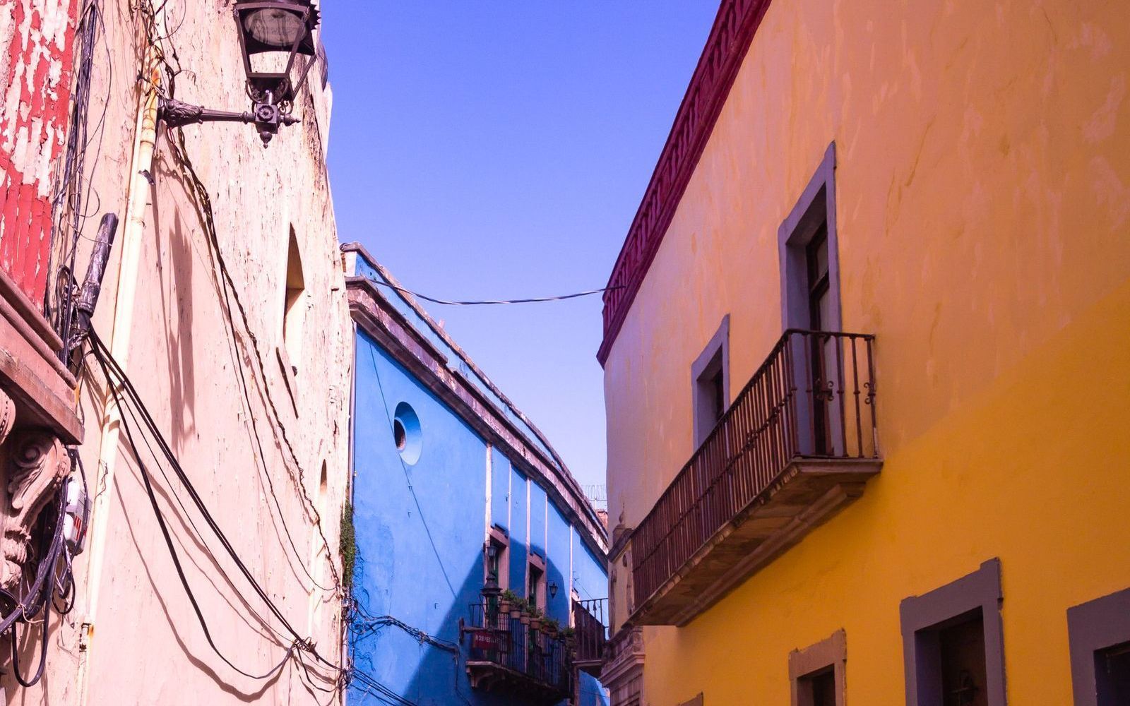 A narrow street lined with colorful stucco homes in a historic barrio